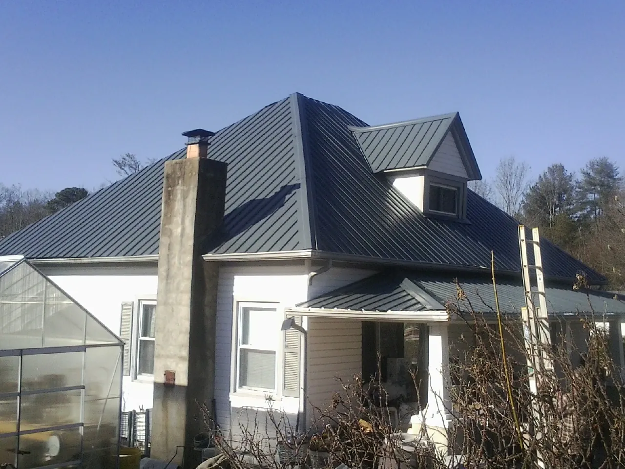 Dark blue standing seam metal roof on a white farmhouse with dormer — Slate & Tile Roof Repair by Roofing Brothers in Chaska