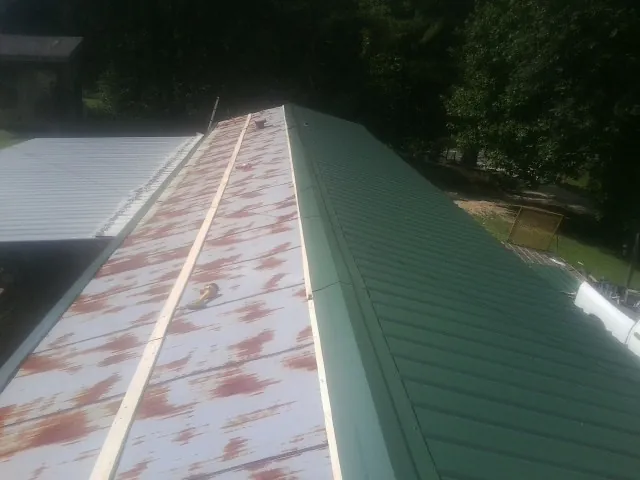 Old rusted panels beside newly installed green metal roofing — Wind Damage Roof Repair by Roofing Brothers in Chaska