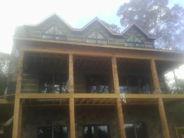 Dormers and porch framing on a large log home under construction — Roof Coating work by our crew in Chaska