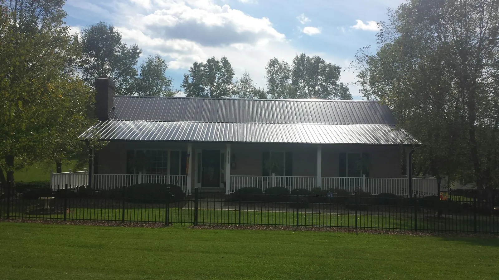 Gray metal roof on a brick ranch with a full width front porch — Gutter Guard Installation work by our crew in Chaska