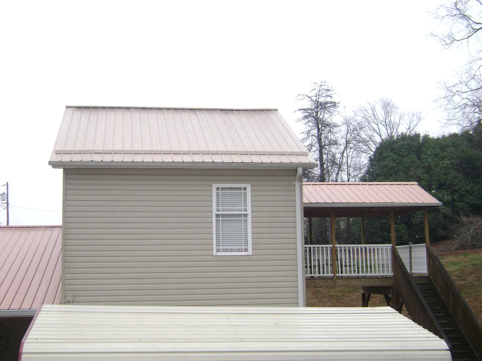 Tan metal roofs on a two story addition and attached porch, from a Roof Replacement job in Chaska