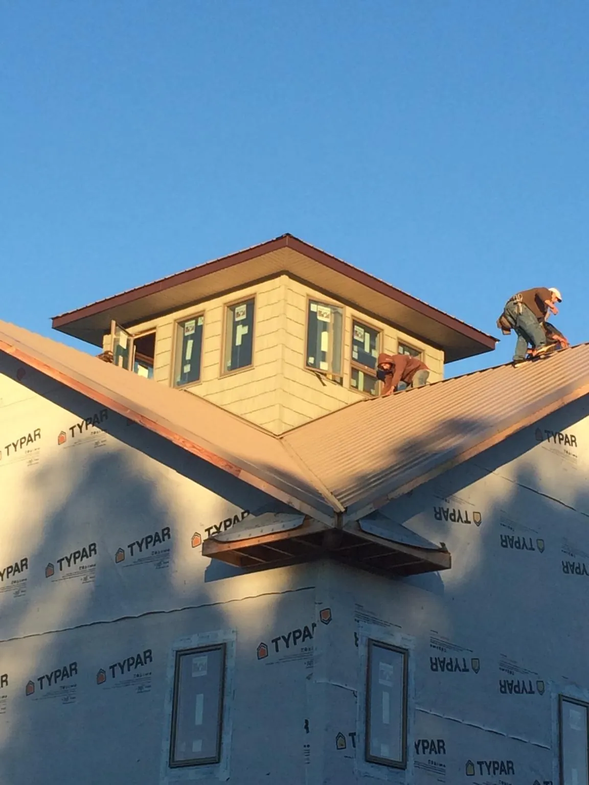 Roofers working around a rooftop cupola on a new metal roof at sunset — Roof Waterproofing in Chaska by Roofing Brothers